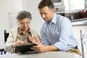 a senior alongside an in-home care agent working together to fill out the forms required for him to begin caregiving for the senior