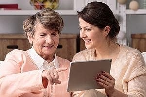 employee of an in-home care agency working with her senior patient to compile a list of household chores that need to be done by the caregiver