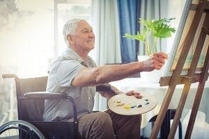 senior man using in home mobility equipment for seniors to paint a picture