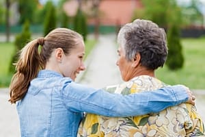 Caregiver helping senior walk outdoors