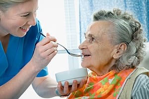 Senior citizen being helped to eat by in home nurse caregiver