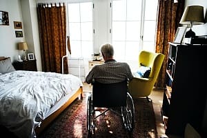 man sitting by himself in his bedroom in a wheel chair