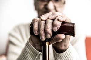 man with his hands on a cane 